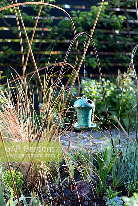 Decorative ceramic bird box suspended on building rail plant support in  town garden, Brixton