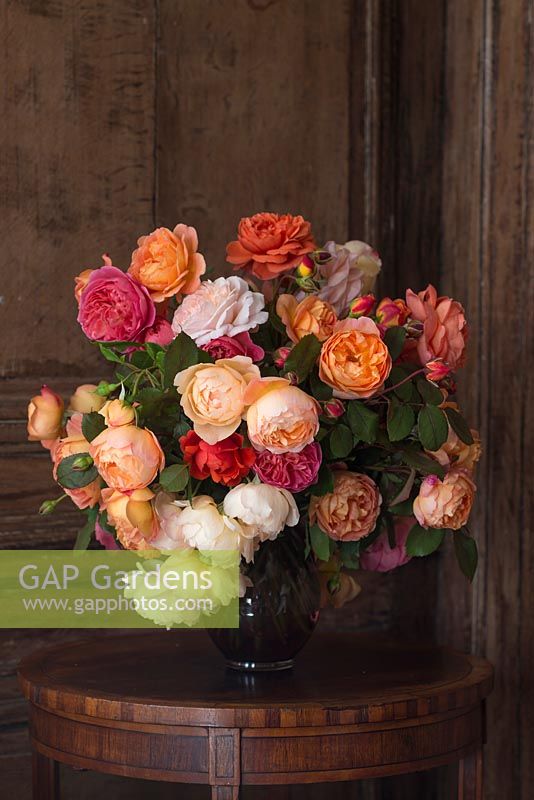 Orange, pink, peach and white roses in a cut flower arrangement on a side table