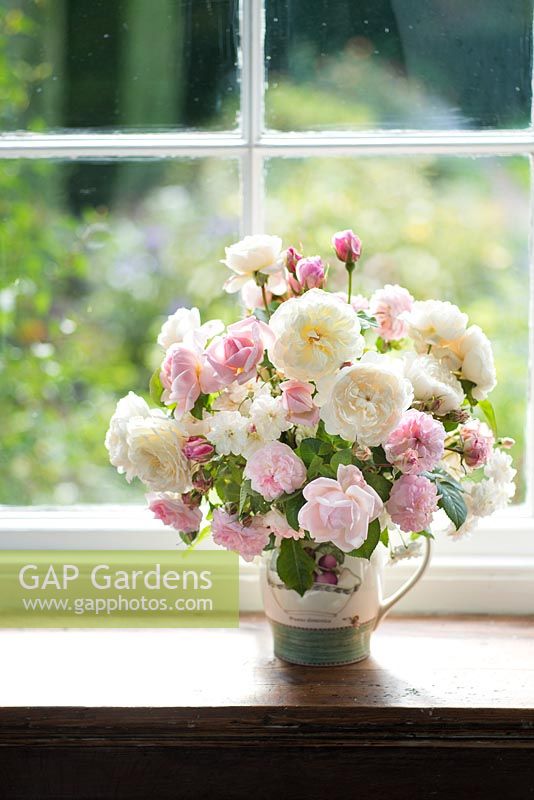 Cut flower arrangement with cream and pink roses on a windowsill