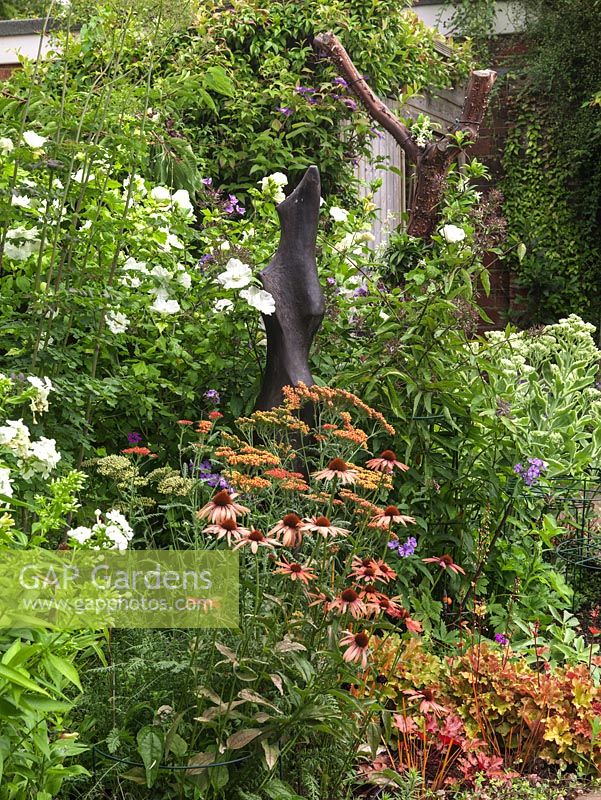 Statue set in bed of Achillea 'Walther Funcke', Echinacea 'Sundown', Phlox paniculata 'White Admiral', sedum, Hibiscus syriacus 'Diana' and star jasmine.