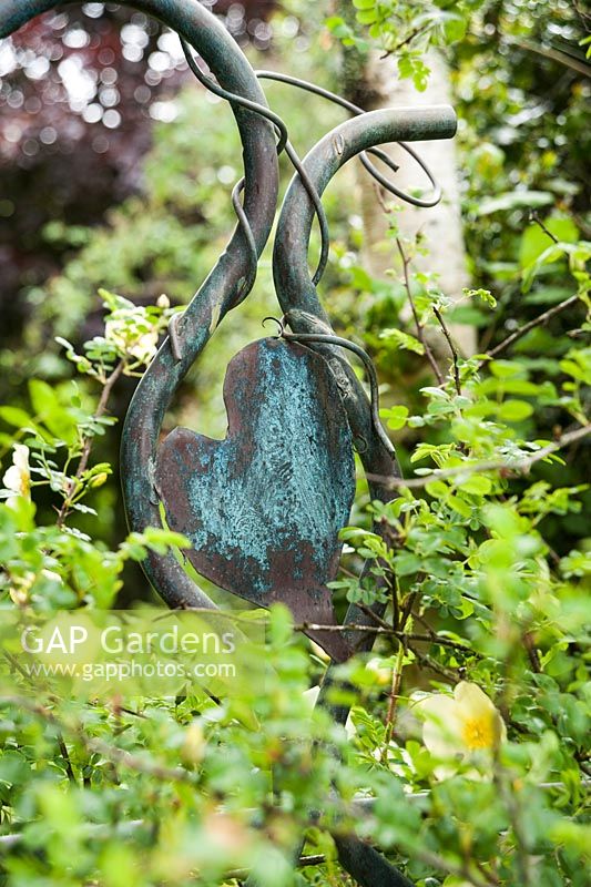 Metal heart topping an archway in the garden. Caervallack Farm, nr Helston, Cornwall, UK