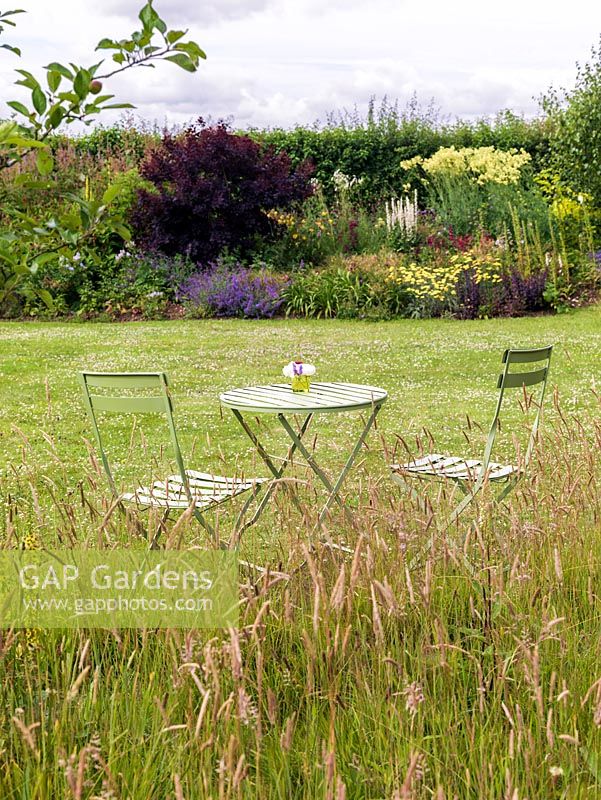 Table and chairs in natural meadow of grasses and wildflowers