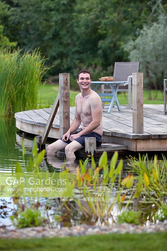 Man relaxing by a swimming pond.