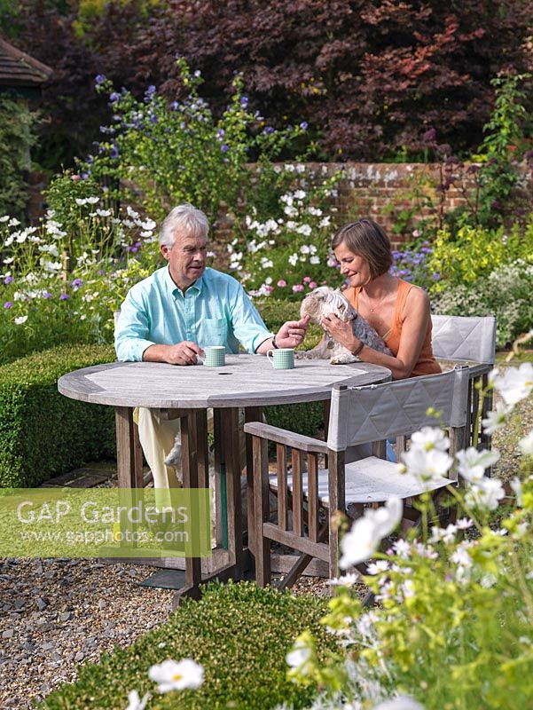 John and Kate Bolsover relax in the cottage garden parterre, along with their dog, Washington.
