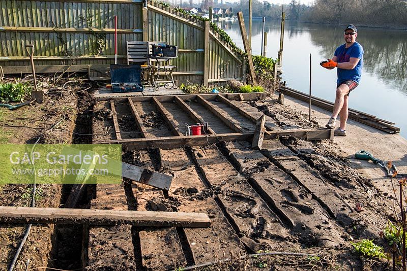 After weeks of flooding, a riverside deck has to be completely rebuilt. The first step is to remove the hardwood decking planks, revealing the softwood subframe which is rotting in parts because a build-up of wet mud has been deposited between the joists.