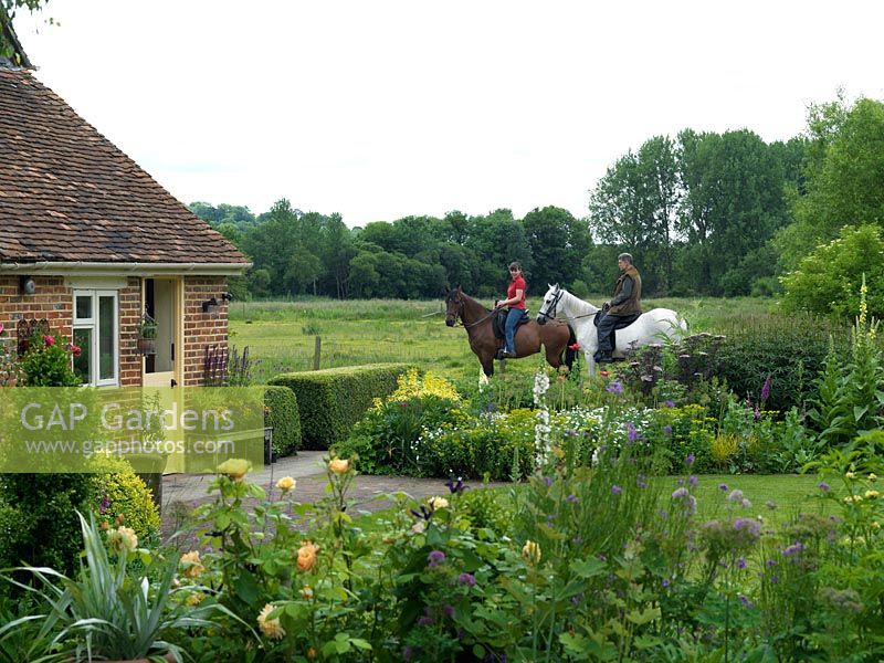 Owner Sandy Burnfield on horseback, accompanied by Sarah Johns, outside his country garden overlooking the River Test valley.
