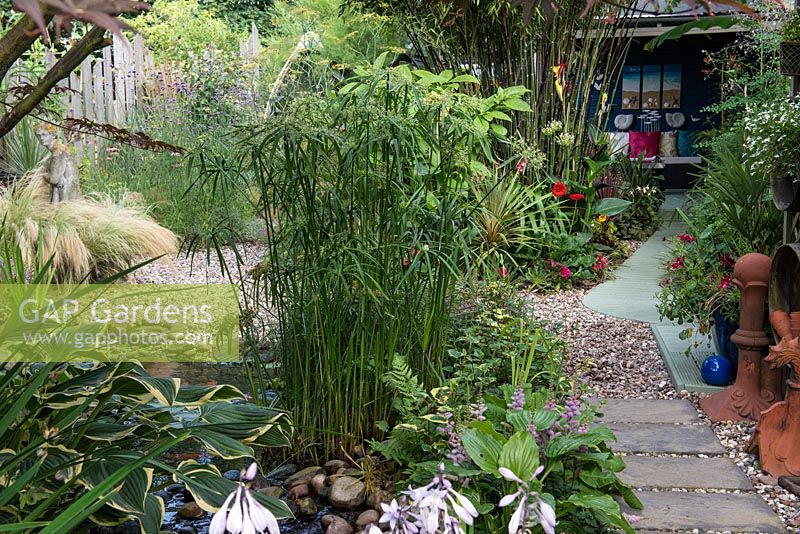 A town garden with covered seating area, gravel bed and fish pond with papyrus.
