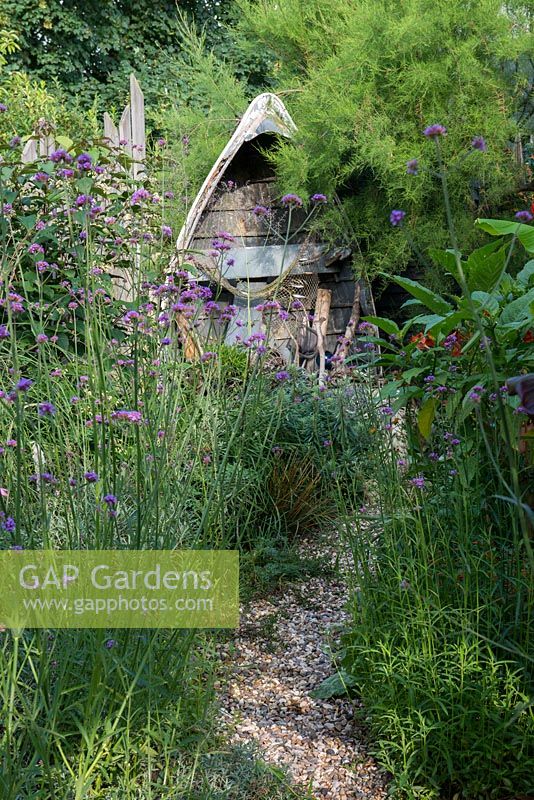 A gravel garden with salvaged seaside decorations seen through Verbena bonariensis.