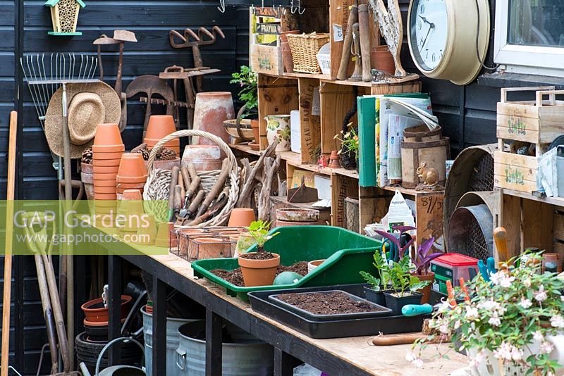 A potting bench with tools, pots and propagation equipment.