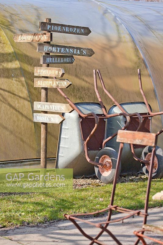 Signs in the outside nursery. Wheelbarrows and chair.