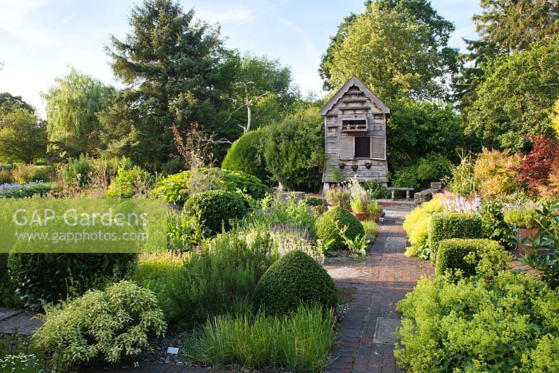 View across Herb Garden in summer towards dovecote, with clipped topiary balls