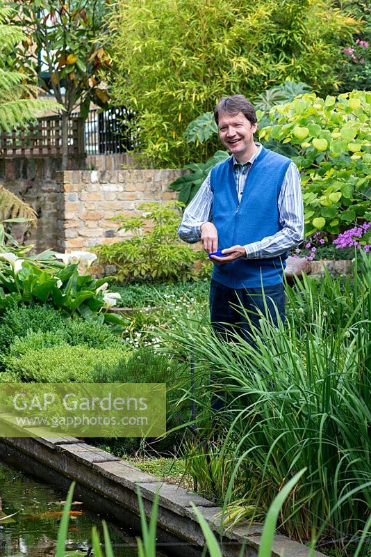 Rupert King who created his water garden on a blank canvas, inspired by Persian Paradise and Japanese gardens. Pictured feeding the fish.