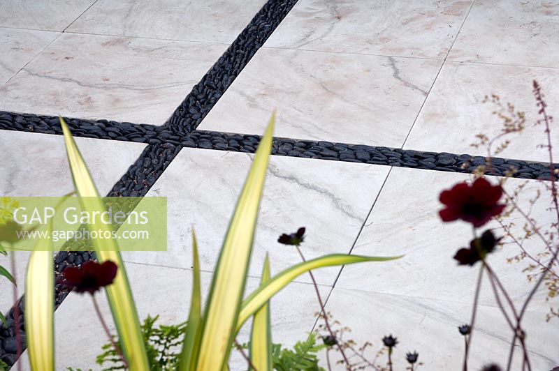 White marble slabbed floor with black pebbles running through the design