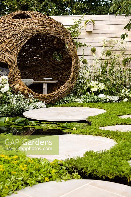 Living Landscapes 'City Twitchers' - view showing circular paved areas, camomile lawn, pond, spherical willow bird hide, nesting box and mixed planting in whites - RHS Hampton Court Flower Show 2015