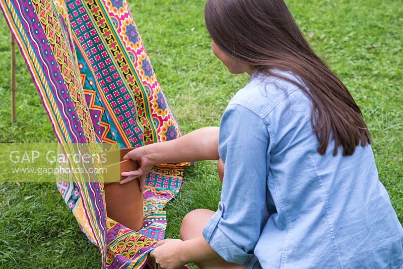 Weigh down the end of the fabric sheet with a heavy empty pot