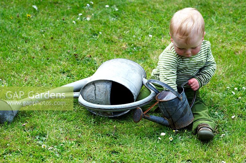 Little boy playing with watering cans