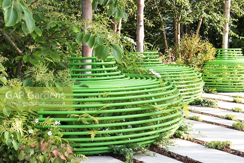 Three green tubular metal seat around Birch trees. Designer Ann-Marie Powell Gardens. Sponsor: Macmillan Cancer Support