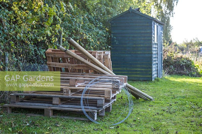 Materials required to construct an upcycled Three-Bin composting system. Wooden pallets, metal wire, strong wooden stakes, a saw and a post driver