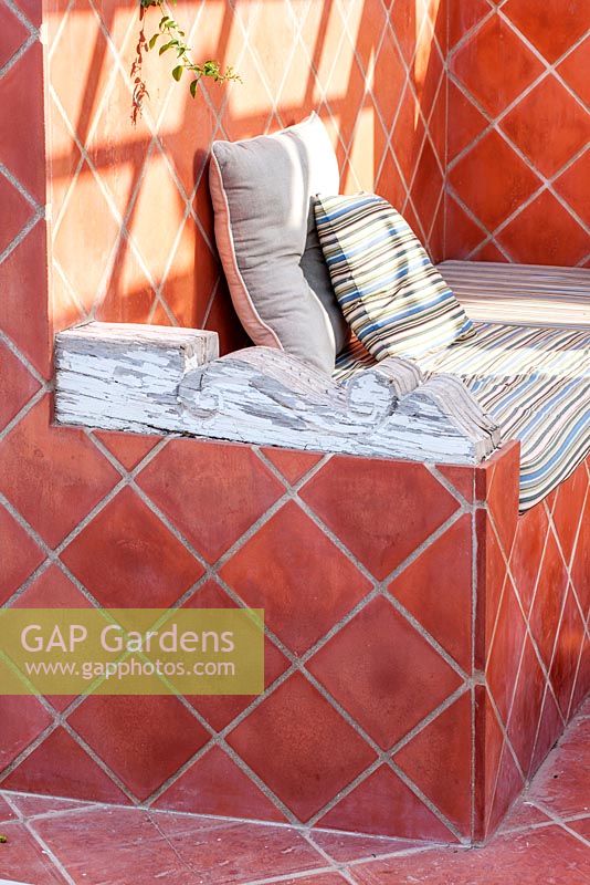 Outdoor terracotta tiled seating area with rustic wooden arm rest.  