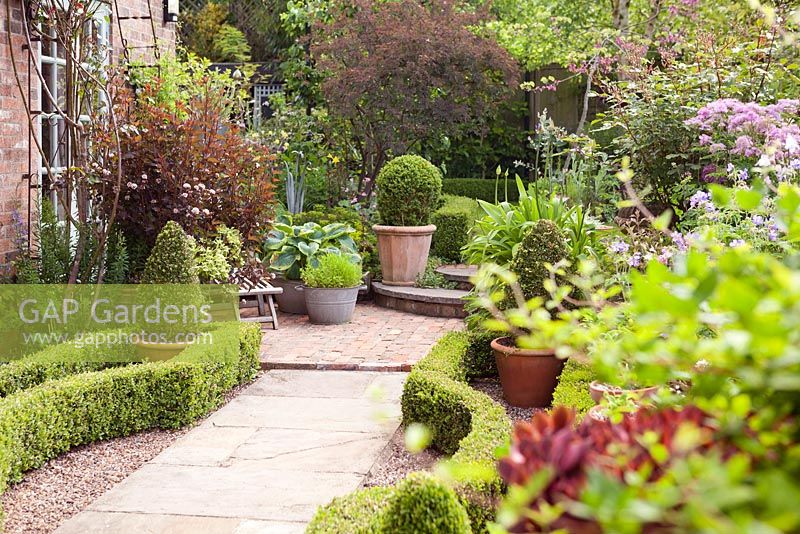 Looking across the parterre with pots of shrubs. Hope House, Caistor, Lincolnshire, UK.