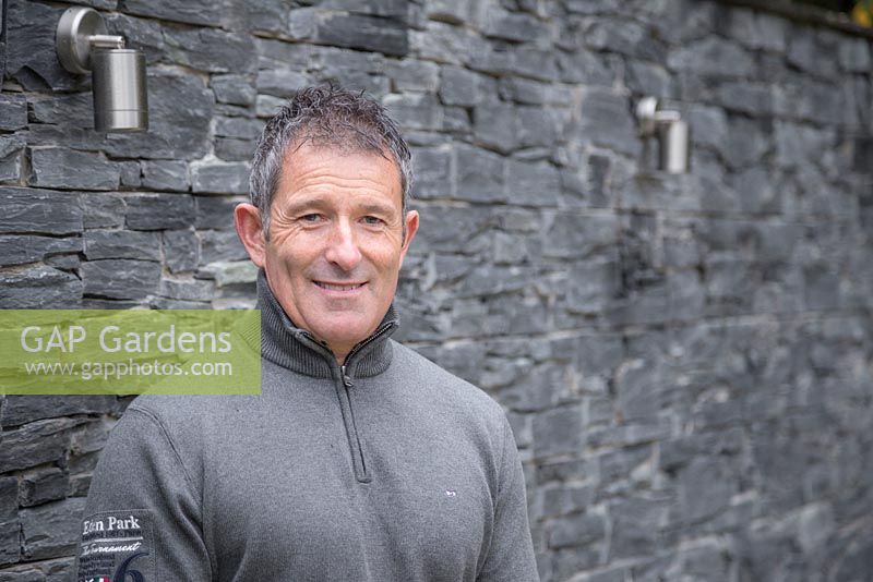 Garden designer Sean Butler of Cube 1994, standing beside lighting features on a dry stone slate wall