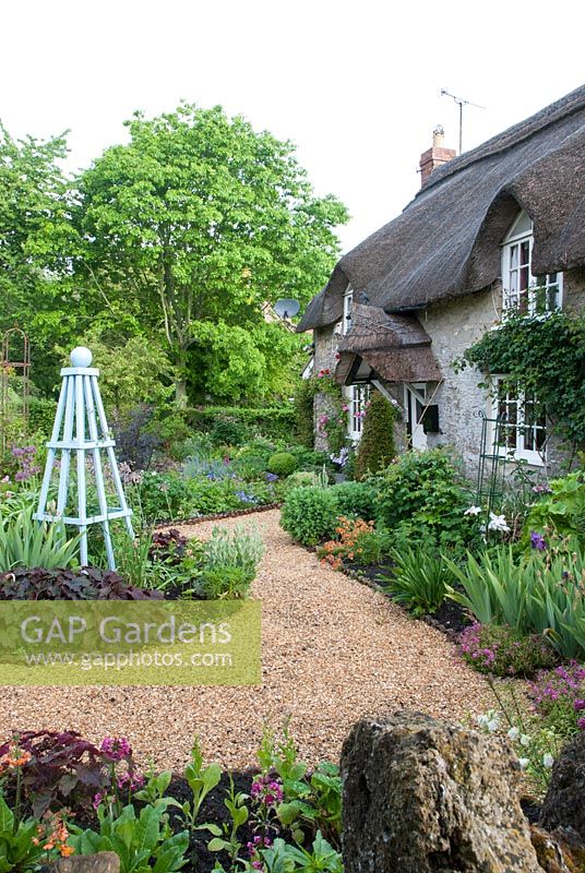 Cottage garden with gravel path and blue painted obelisk