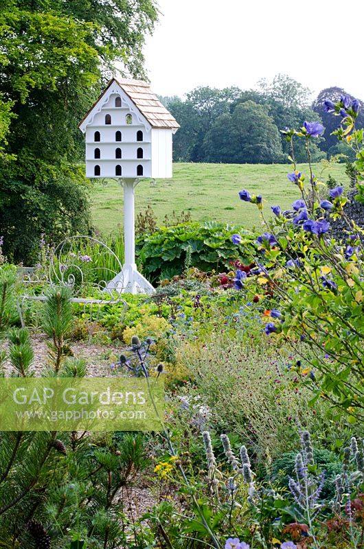 Dovecote by Gerry Peachey, Hibiscus syriacus 'Oisaeu Bleu' and  Pinus nigra - Corsican Pine in the foreground - The Walled Garden at Mells, Somerset