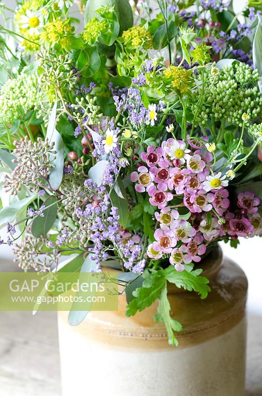 Cut flowers in a stoneware jar including Sedum, Limonium platyphyllum - Sea lavender, Eucalyptus and Bupleurum rotundifolium