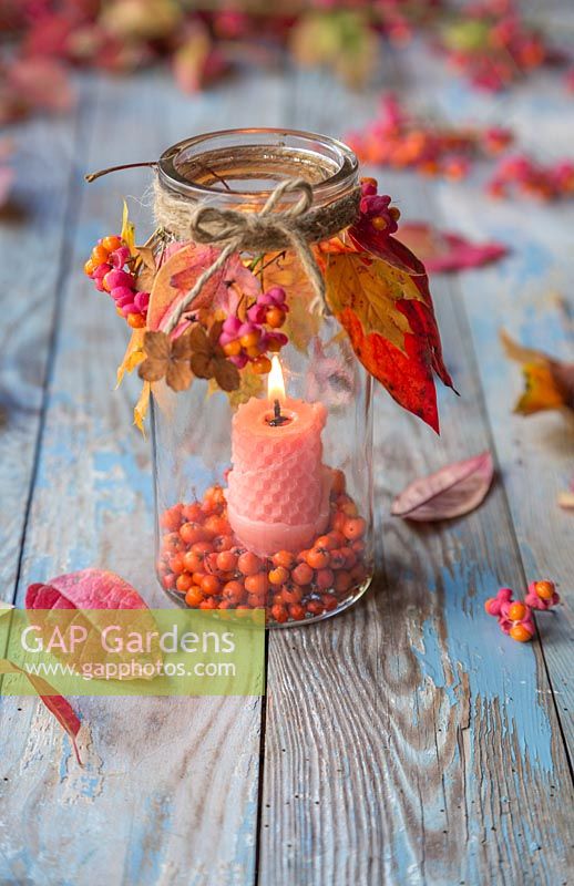 A glass jar candle holder decorated with autumnal foliage, Spindle and Pyracantha berries