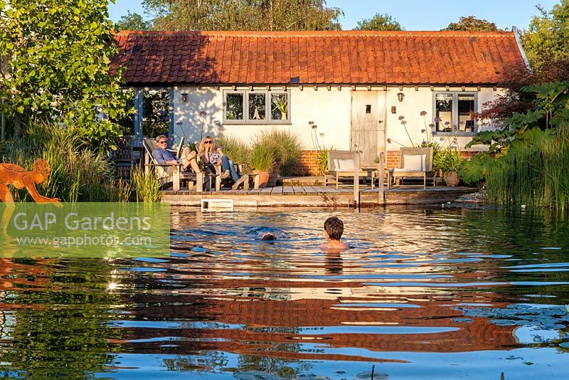 Family relaxing by and swimming in a swimming pond