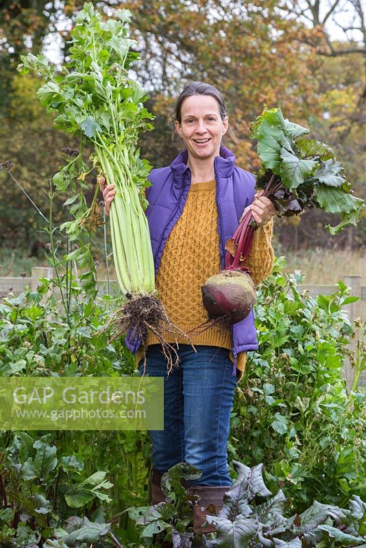 Woman holding overgrown produce of beetroot and celery