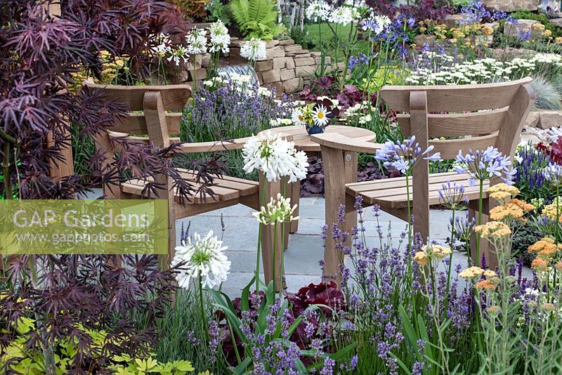 Profusely planted seating area with a view of the waterfall in 'The Water Garden' at RHS Tatton Flower Show 2015