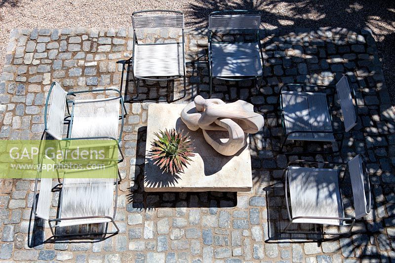 View of cobbled seating area with wooden sculpture in the sun and shadows. USA, August.