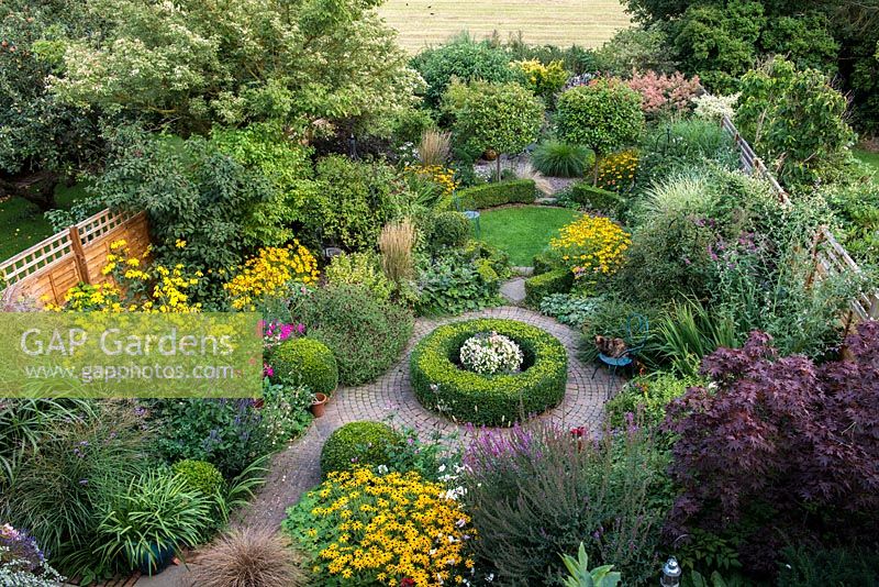 An overhead view of a south facing suburban garden designed around interlinking circles. Deep borders are mainly herbaceaous with shrubs and shaped box providing structure and framing the planting throughout the year.