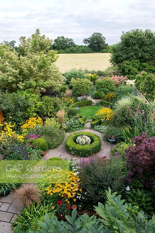 An overhead view of a south facing suburban garden designed around interlinking circles. Deep borders are mainly herbaceaous with shrubs and shaped box providing structure and framing the planting throughout the year.