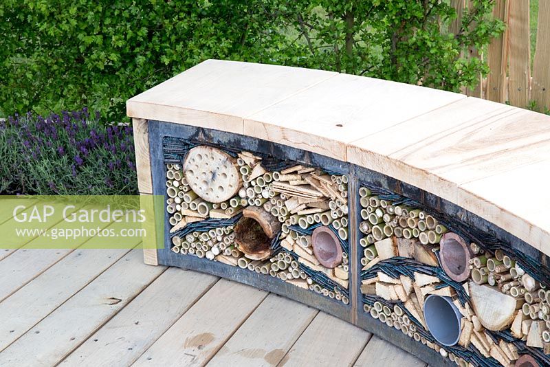 Wildlife friendly garden, reclaimed wooden garden bench with insect shelter, drilled logs, bamboo and old carpet, reclaimed timber decking - The Sanctuary Garden for St Michael's Hospice, designed by Hannah Genders, RHS Malvern Spring Festival 2015