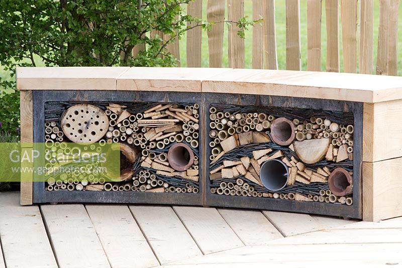 Wildlife friendly garden, reclaimed wooden garden bench with insect shelter, drilled logs, bamboo and old carpet, reclaimed timber decking - The Sanctuary Garden for St Michael's Hospice, designed by Hannah Genders, RHS Malvern Spring Festival 2015
