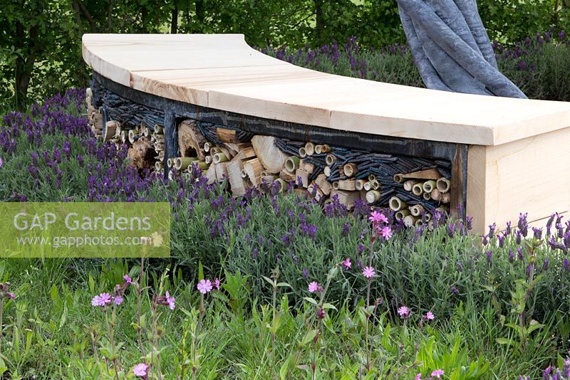 Wildlife friendly garden, reclaimed wooden garden bench with insect shelter, drilled logs, bamboo and old carpet, planting of French lavender The Sanctuary Garden for St Michael's Hospice, designed by Hannah Genders, RHS Malvern Spring Festival 2015