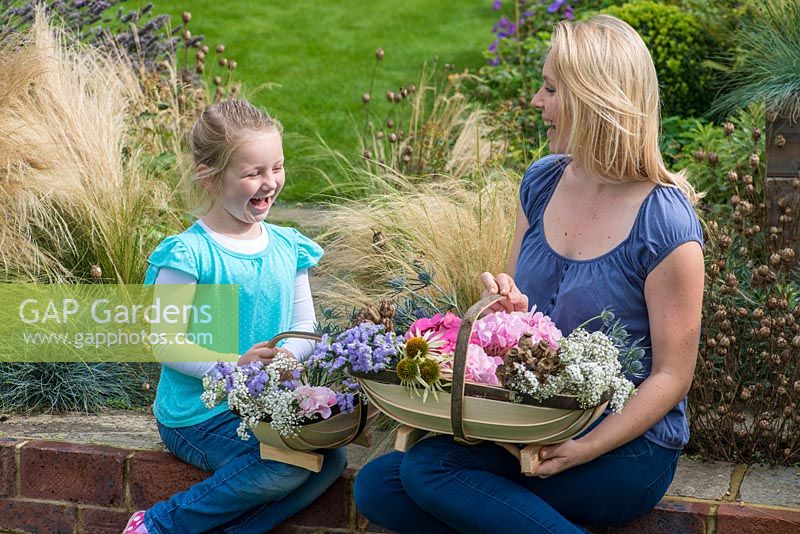 Mother and daughter with their Sussex trugs, handcrafted by Charlie Groves, filled with cut flowers.