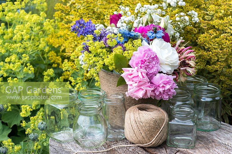 Making a summer posie for freshly cut flowers in glass jars covered with twine.