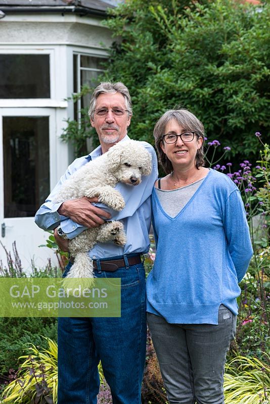 Laura Wahburn Hutton, cookery writer and Ian Pollock in their London garden with Ted, a bichon frise dog.