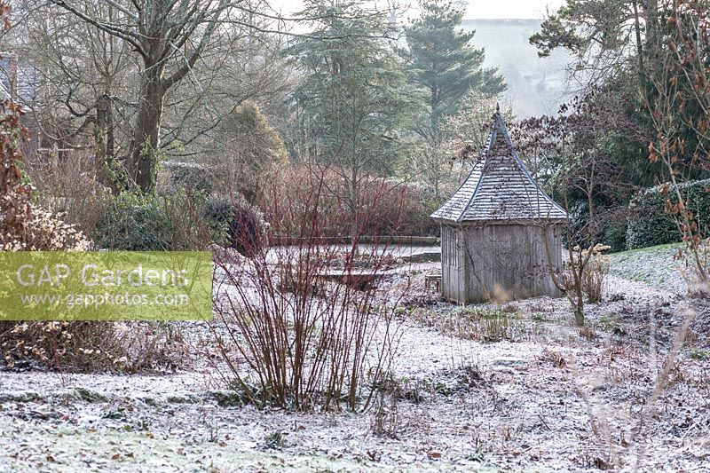 Wooden summerhouse in a dormant bog garden dusted with a light icing of snow.