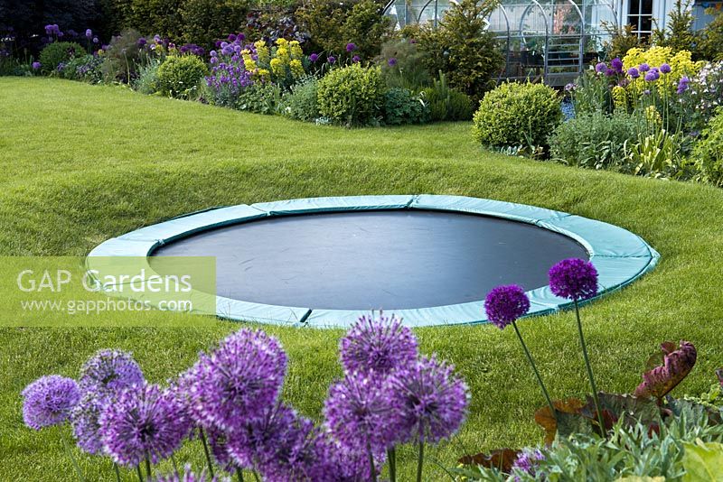 A trampoline set in a raised circle of lawn so that from a distance it is largely concealed.