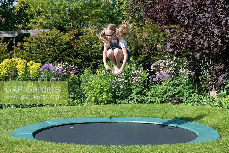 11-year-old Ava on the trampoline, set into the lawn.