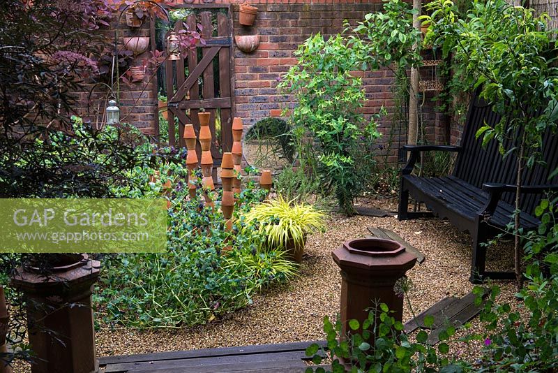 A small gravel garden with recycled terracotta pot sculpture providing a focal point.