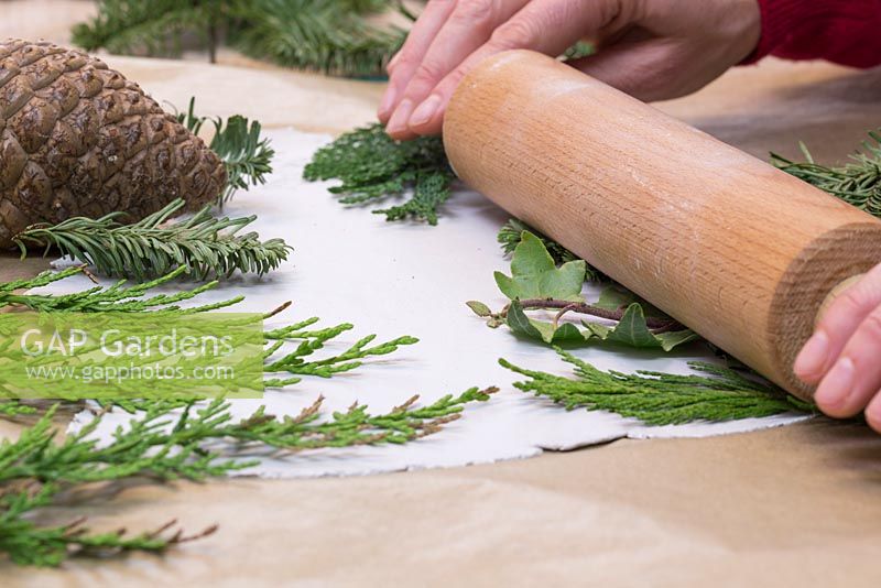 Using a rolling pin to gently apply an imprint into the clay, using a variety of foliage