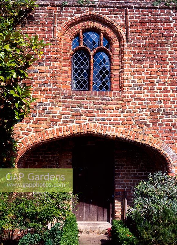 Sissinghurst Castle - the entrance court, brick house front with arch to door, July