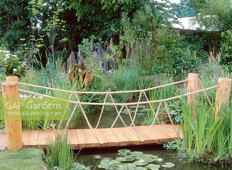 Wood and rope bridge over stream, marginal and aquatic planting, Credit Hampton Court 2001. Design Mark Davis, tranquility