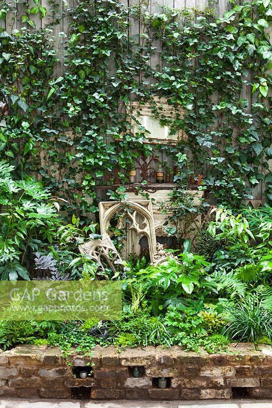 View of border in court yard garden with fire place and church featues, Lucille Lewins, small office court yard garden in Chiltern street studios, London. Designed by Adam Woolcott and Jonathan Smith 