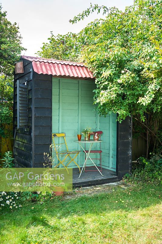 Mini garden pavilion with table and chairs and blue green interior.